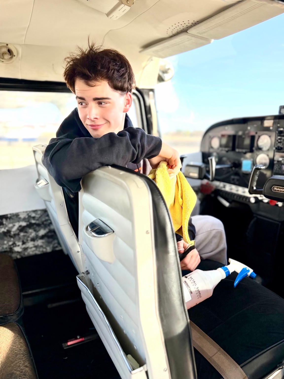 Jack inside an aircraft cabin, holding a yellow cloth beside detailing supplies