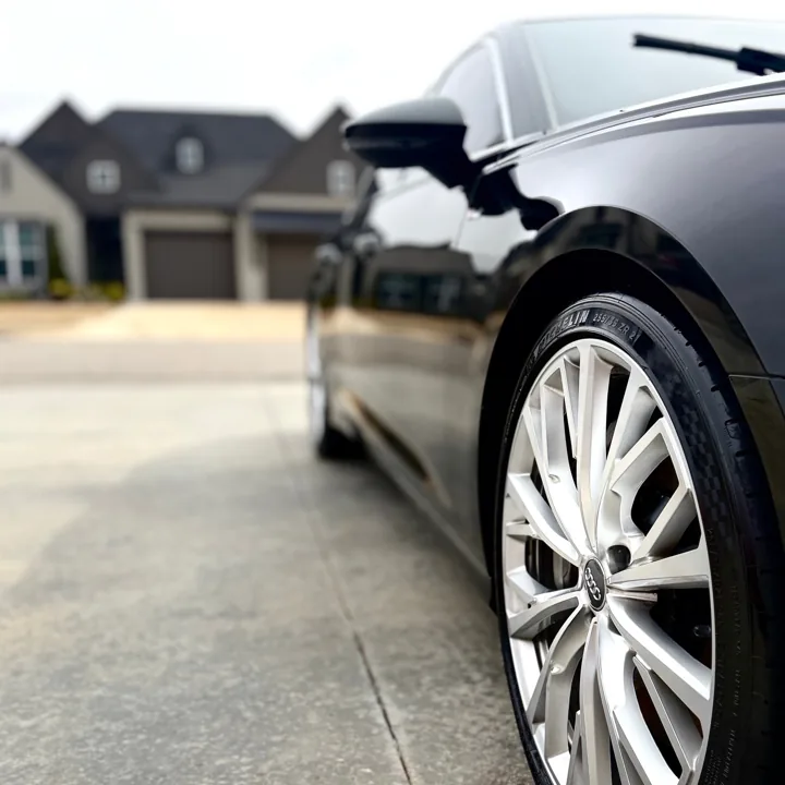 Silver wheel and glossy side of a black Audi sedan