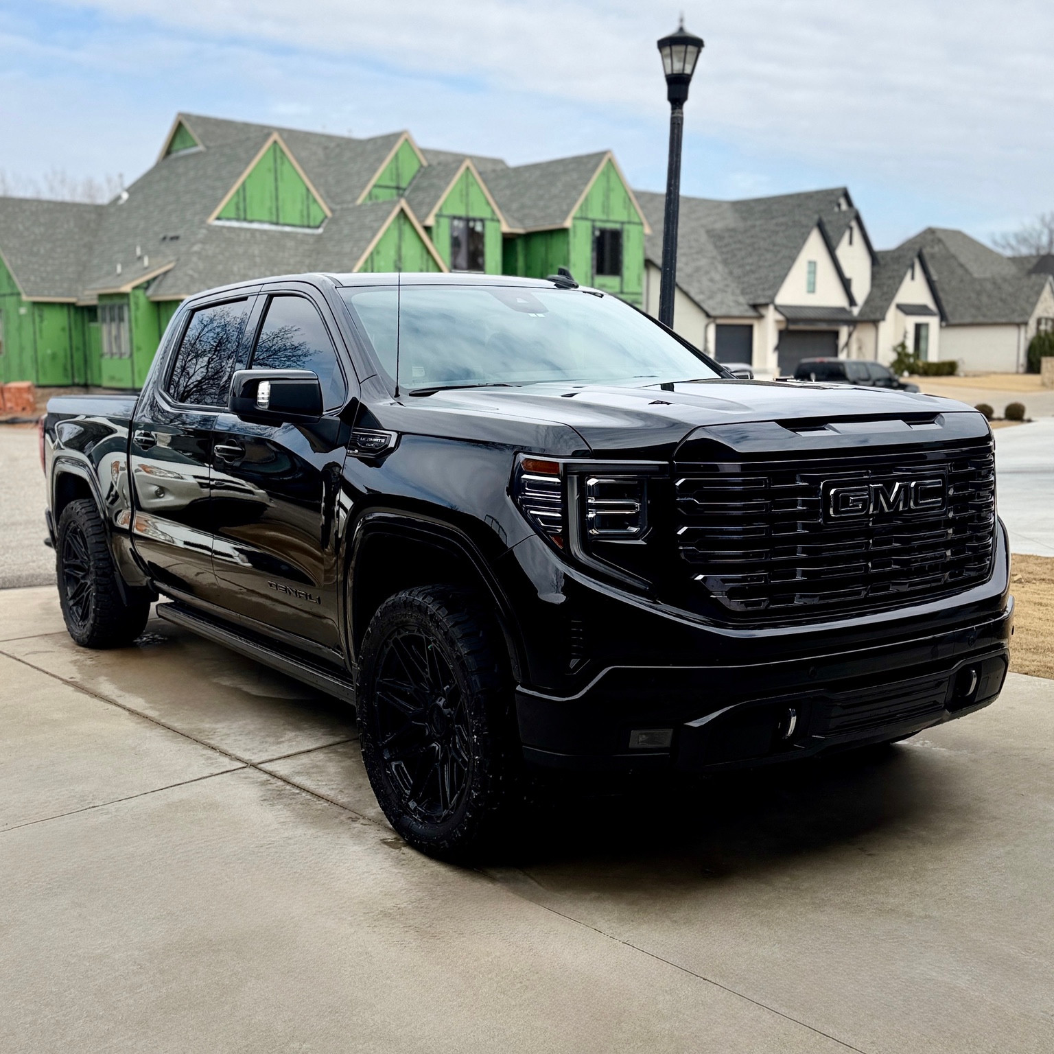 Glossy black GMC pickup with black wheels, shown from roof to tires in an original Falcon photograph