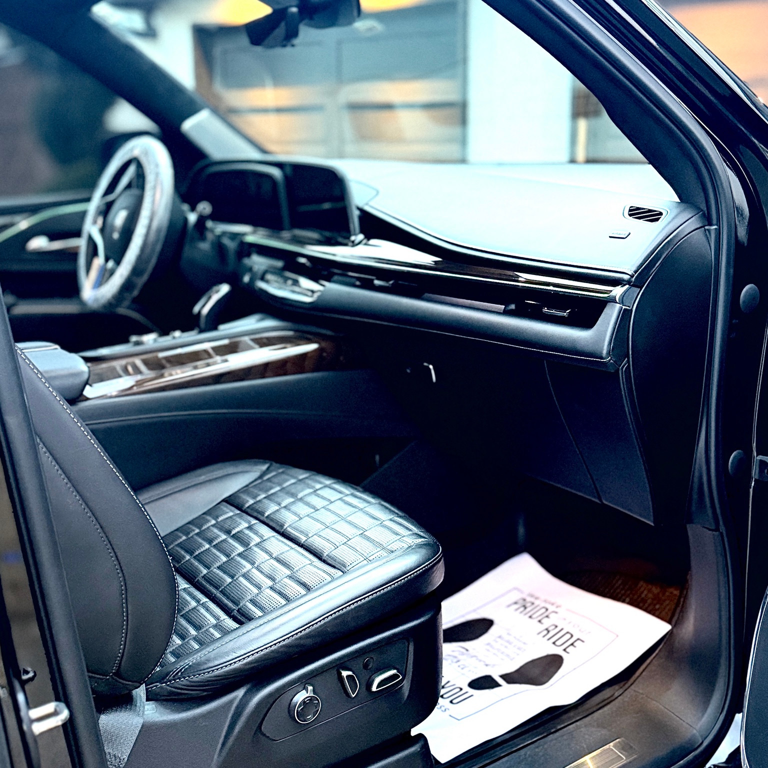 Clean black Cadillac passenger seat, center console and dashboard with protected steering wheel
