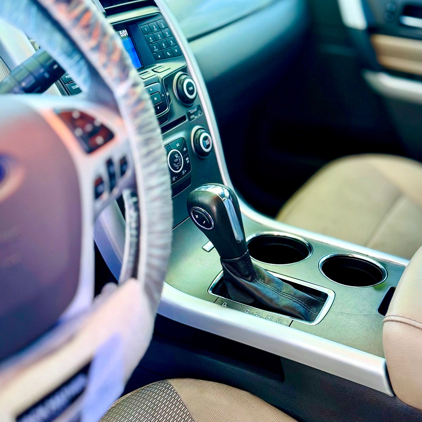 Center console, gear selector and cupholders beside a cloth seat