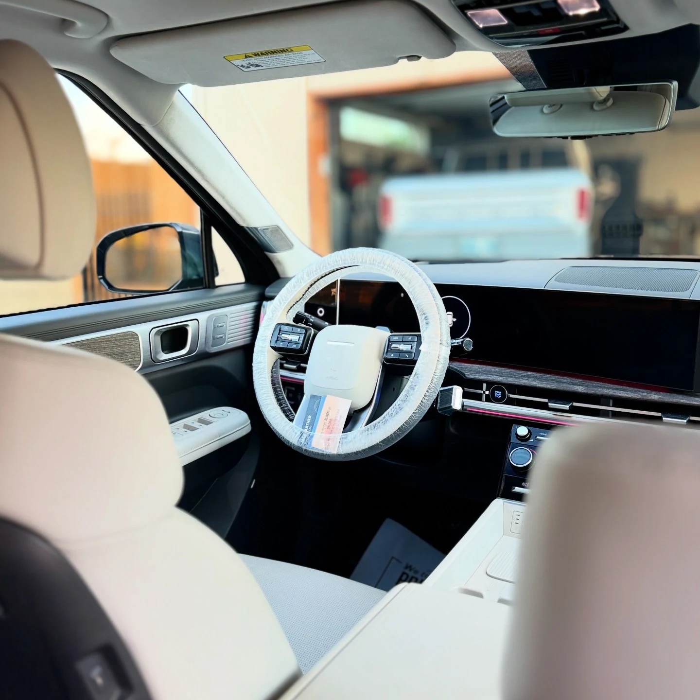 Light cream vehicle interior with a clean dashboard and protected steering wheel