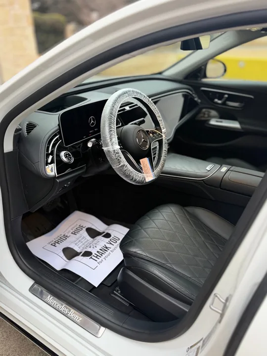 Clean Mercedes interior with leather seat, protected steering wheel and floor mat