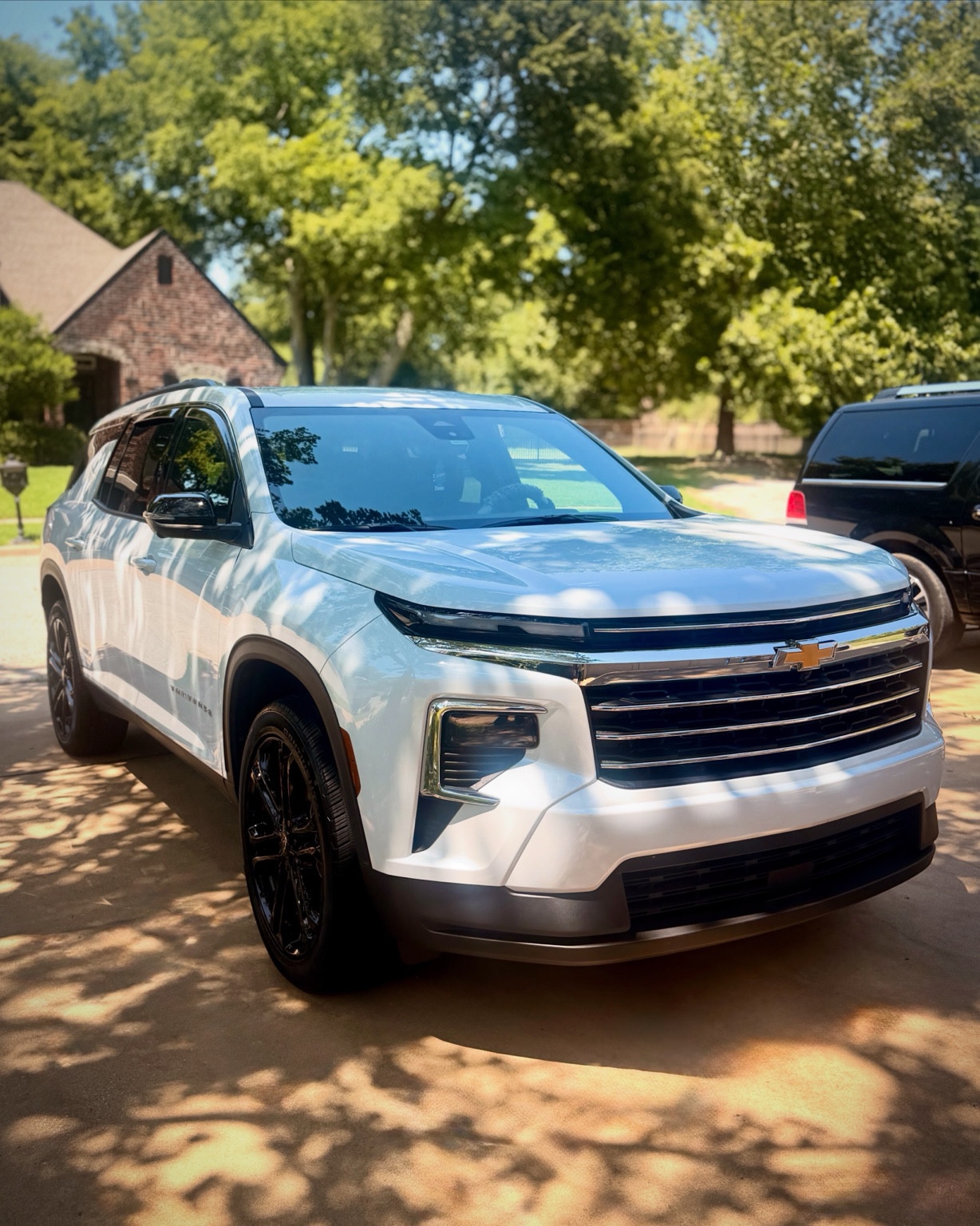 Clean silver Chevrolet SUV in a tree-lined driveway