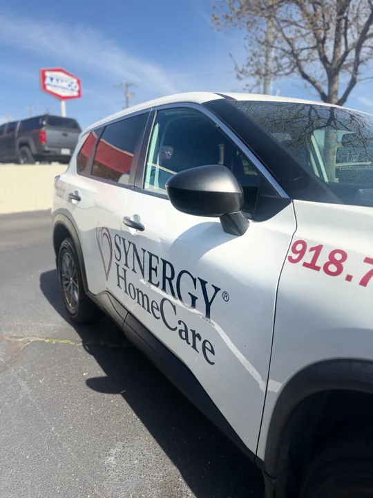 White Synergy HomeCare-branded SUV side and mirror in sunlight