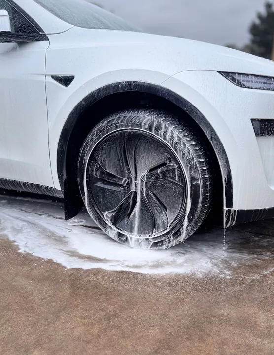 White Tesla front wheel and bodywork covered in wash foam